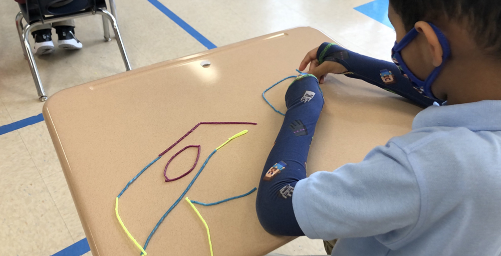 A Syracuse Academy of Science and Citizenship student creates shapes using string as part of a math lesson. A Syracuse Academy of Science and Citizenship student creates shapes using string as part of a math lesson.